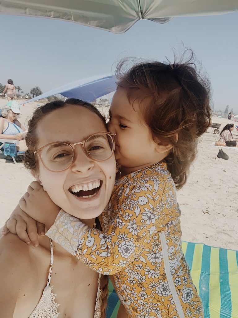 Daughter kissing mother on the face at the beach