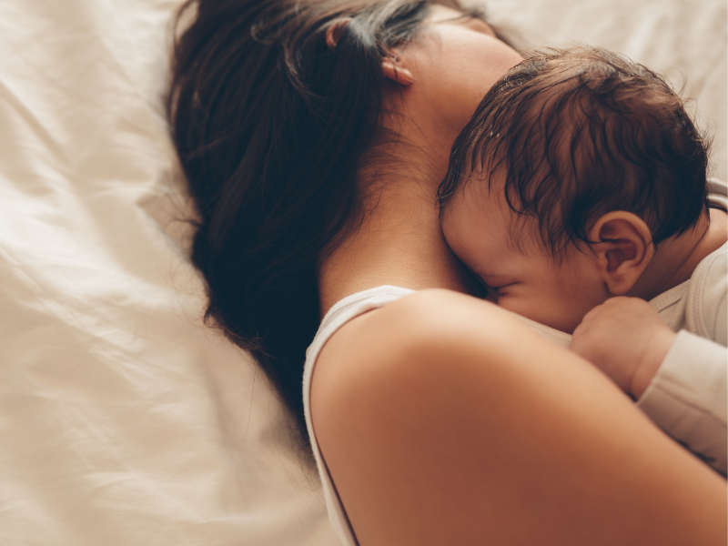 mother holding her baby in bed