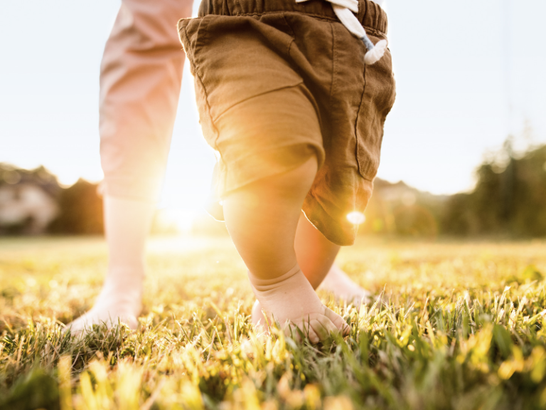 mother and baby running barefoot through the grass