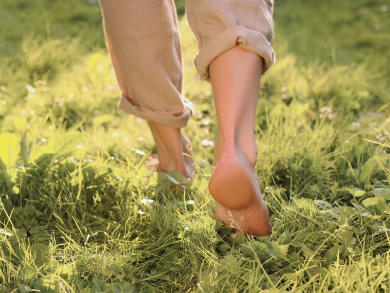 A woman is walking barefoot through the grass