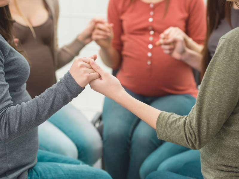 Pregnant women are meeting together, holding hands