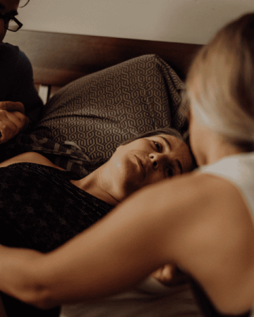 Laboring woman is being supported by her husband and midwife as she labors on the bed.